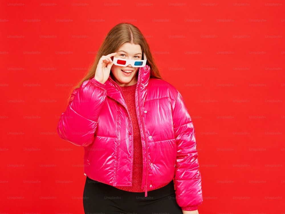 a woman in a pink jacket holding a pair of 3d glasses