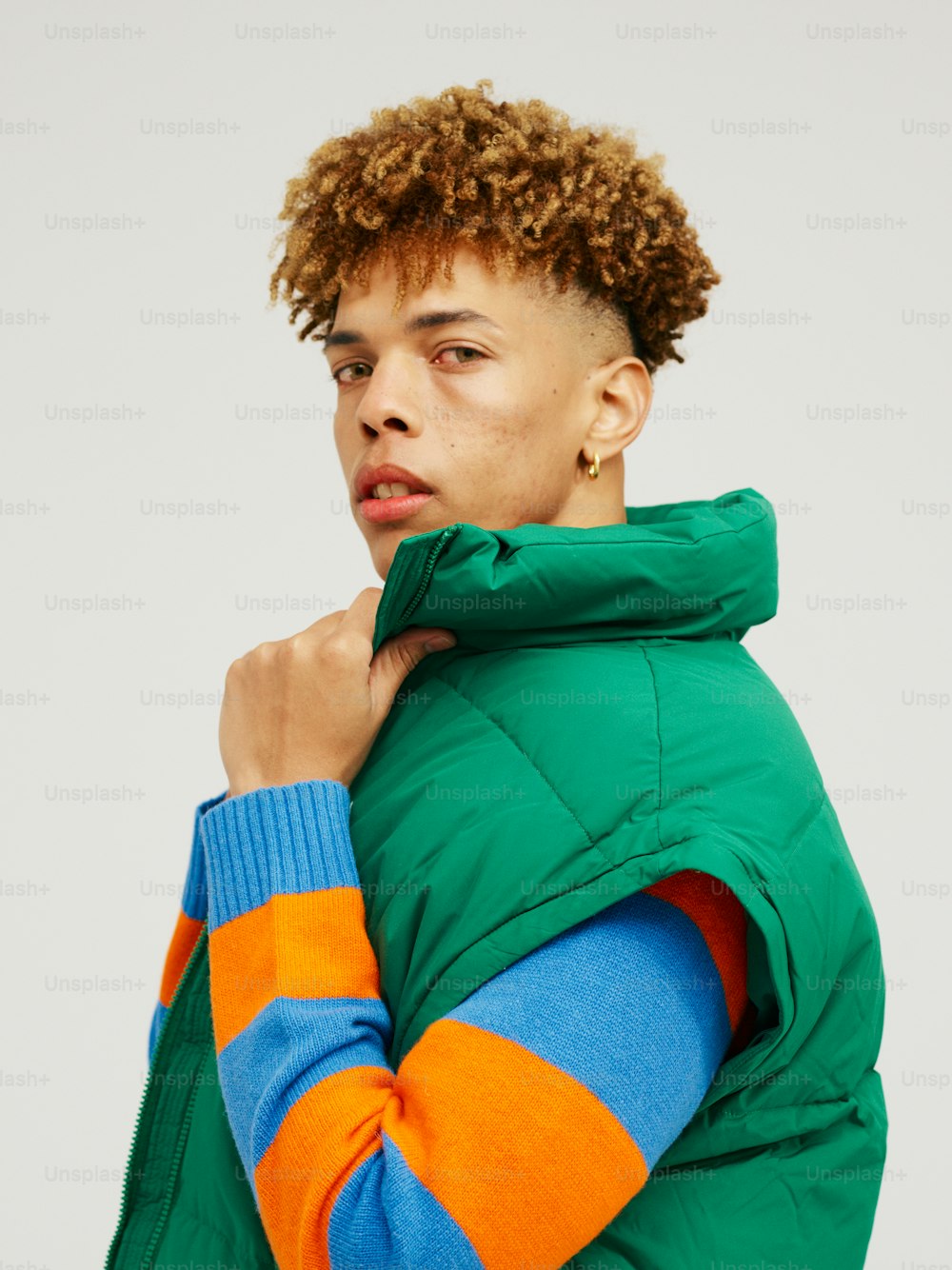 a man with curly hair wearing a green jacket