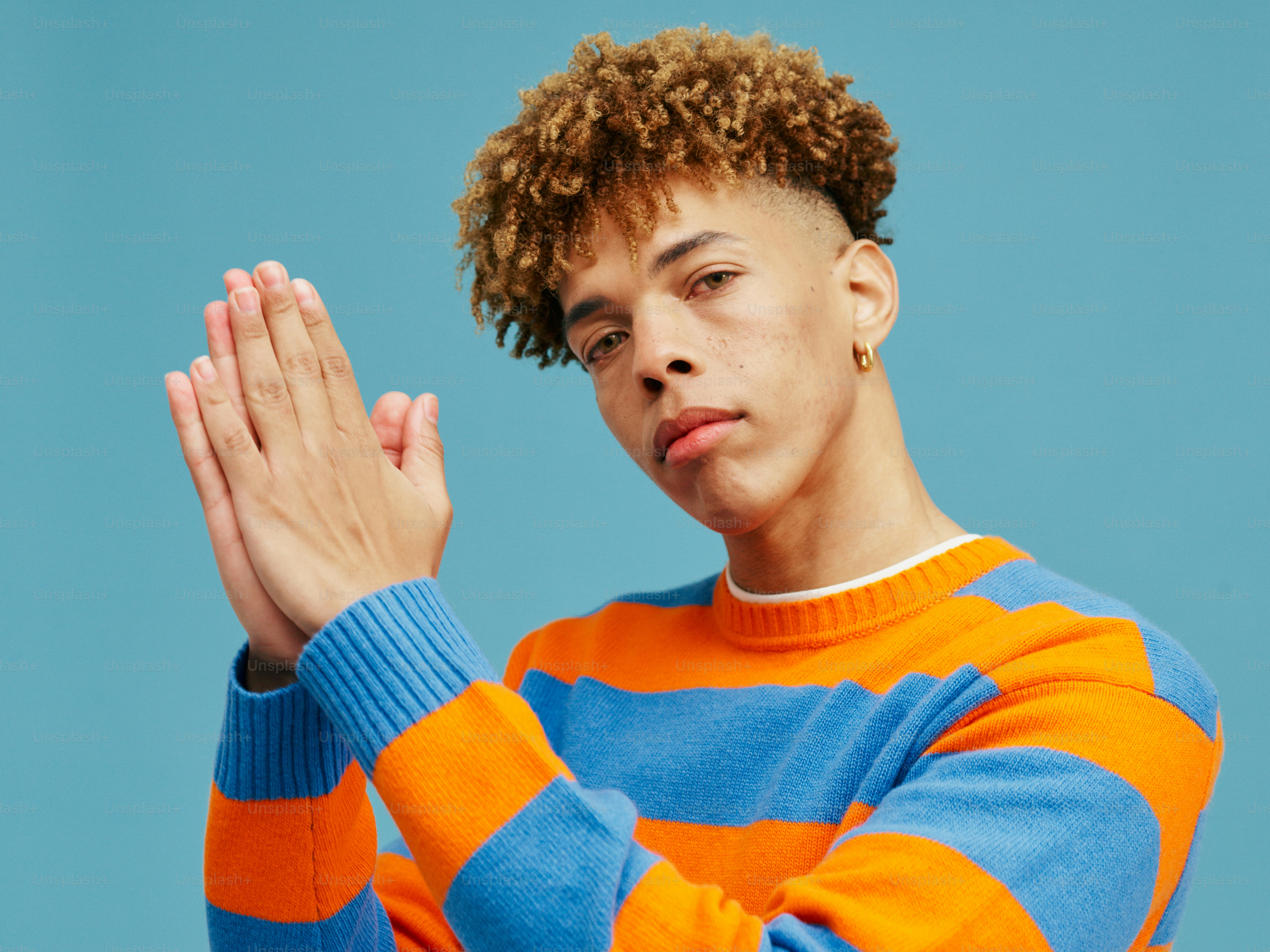 a young man with curly hair wearing a striped sweater