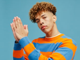 a young man with curly hair wearing a striped sweater