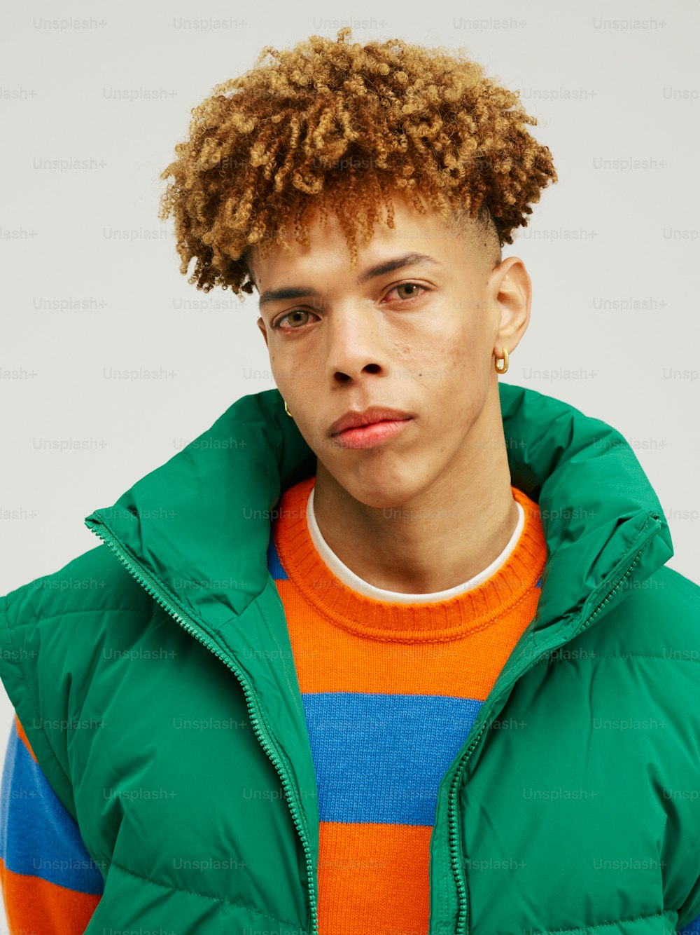 a young man with curly hair wearing a green jacket