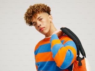 a man with curly hair wearing an orange and blue striped sweater