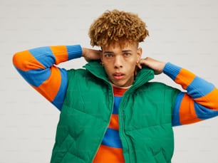 a young man with curly hair wearing a green vest