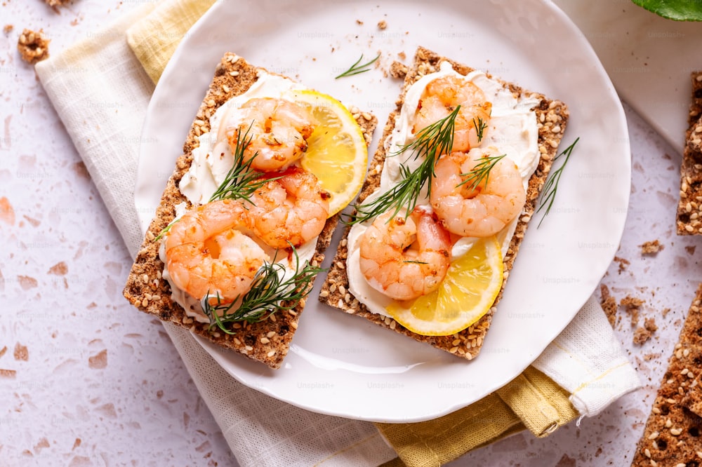a white plate topped with two pieces of bread covered in shrimp