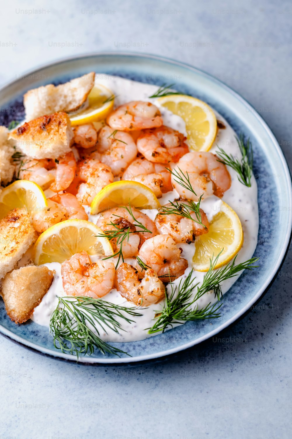 a plate of shrimp with lemon wedges and dill