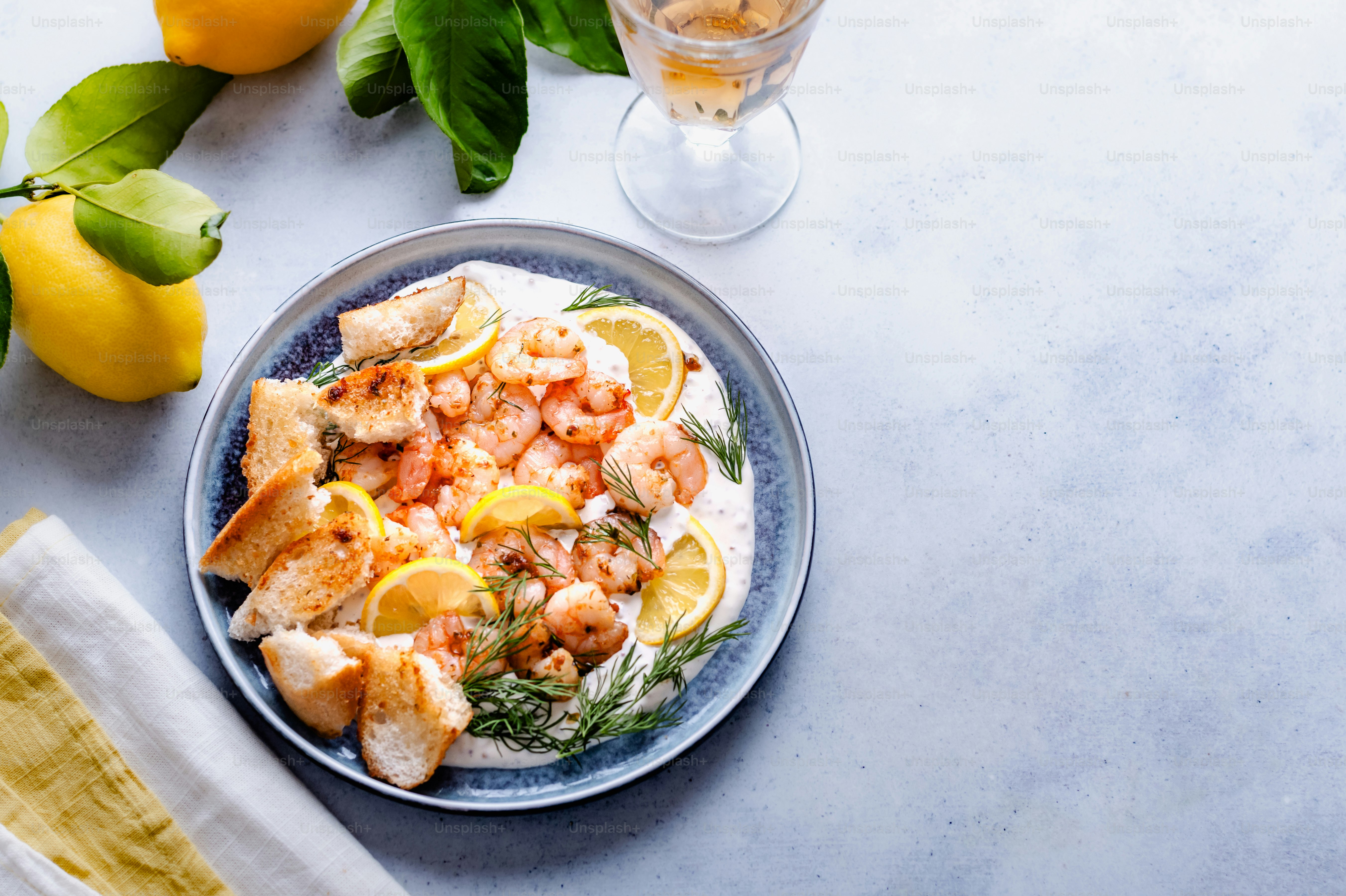 a blue plate topped with shrimp and lemons next to a glass of water