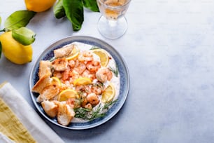 a blue plate topped with shrimp and lemons next to a glass of water