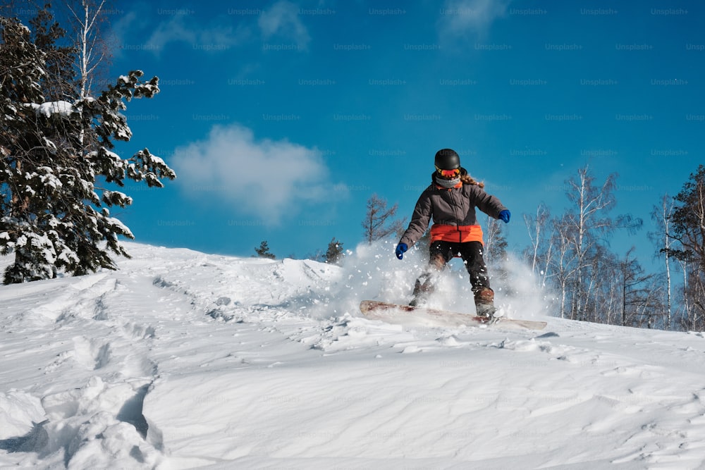 a person riding a snowboard down a snow covered slope