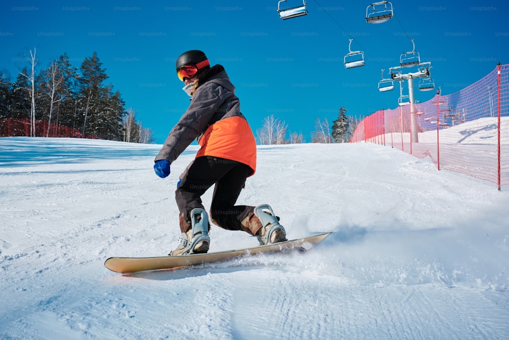 a man riding a snowboard down a snow covered slope