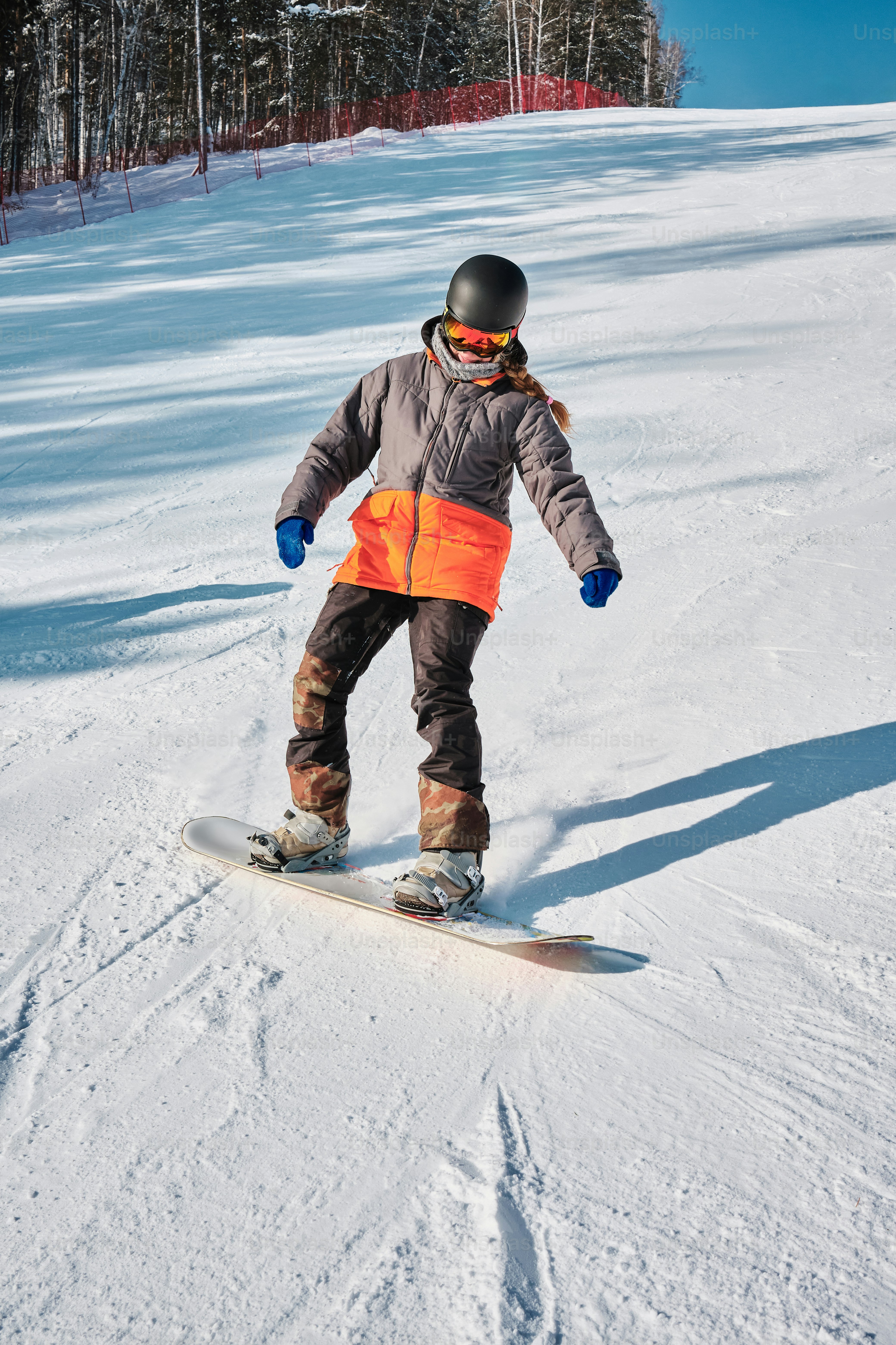 A man riding a snowboard down a snow covered slope photo – Snowboarding ...