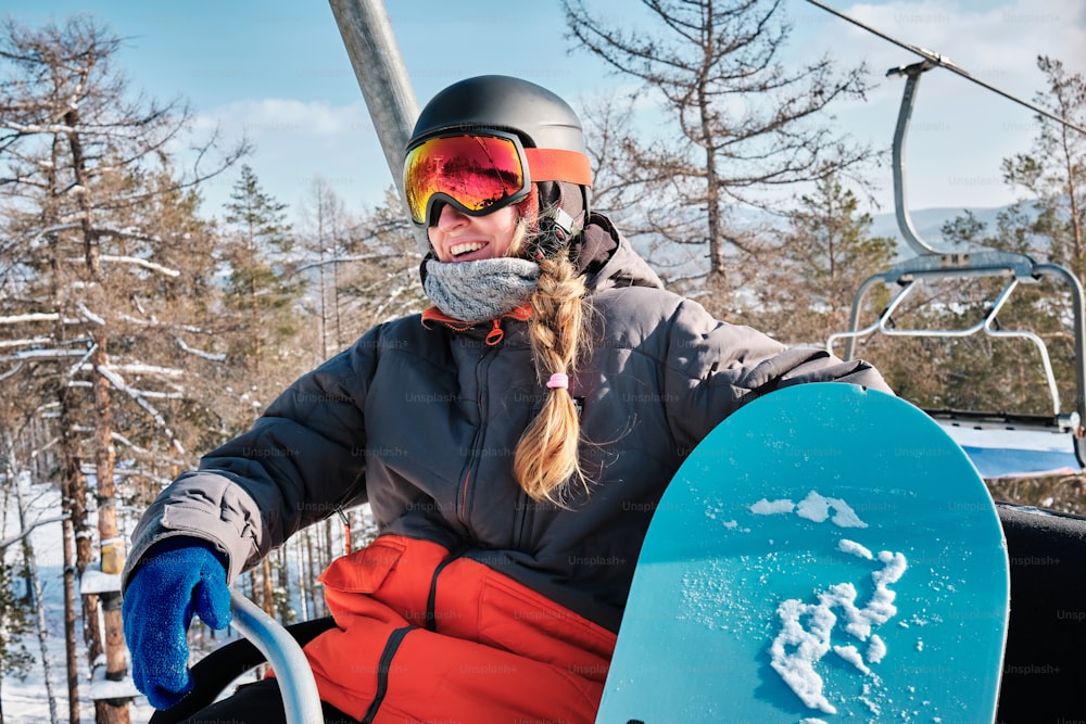 a woman riding a ski lift holding a snowboard
