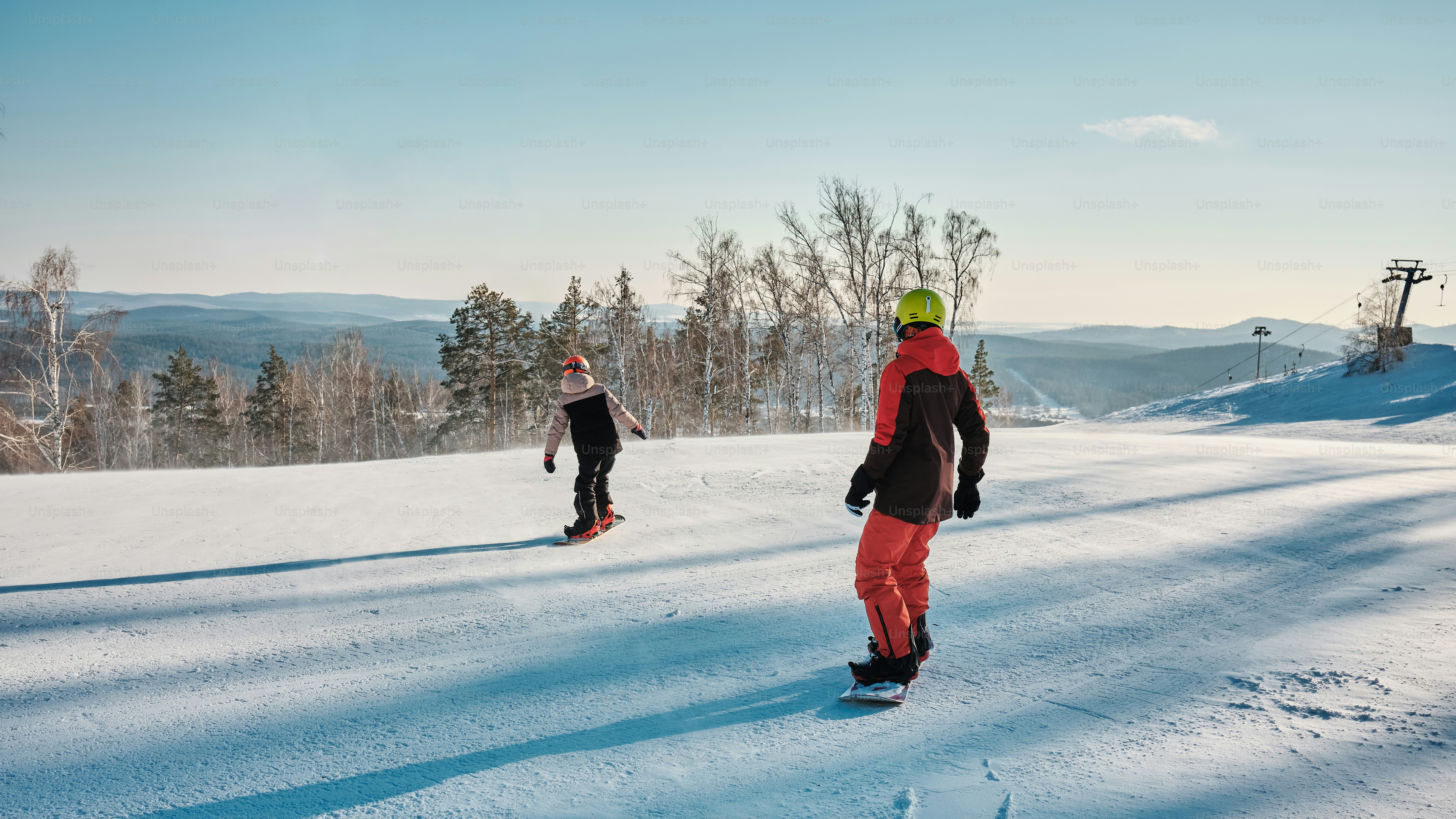 Un paio di persone che vanno con lo snowboard lungo un pendio innevato