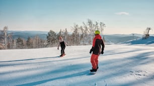 a couple of people riding snowboards down a snow covered slope