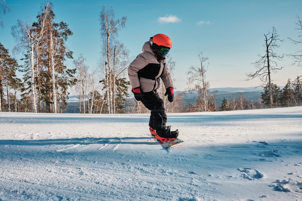 ein Mann, der mit einem Snowboard einen schneebedeckten Hang hinunterfährt