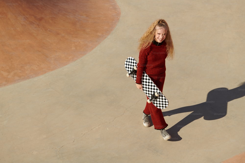 a young girl in a red sweater holding a skateboard