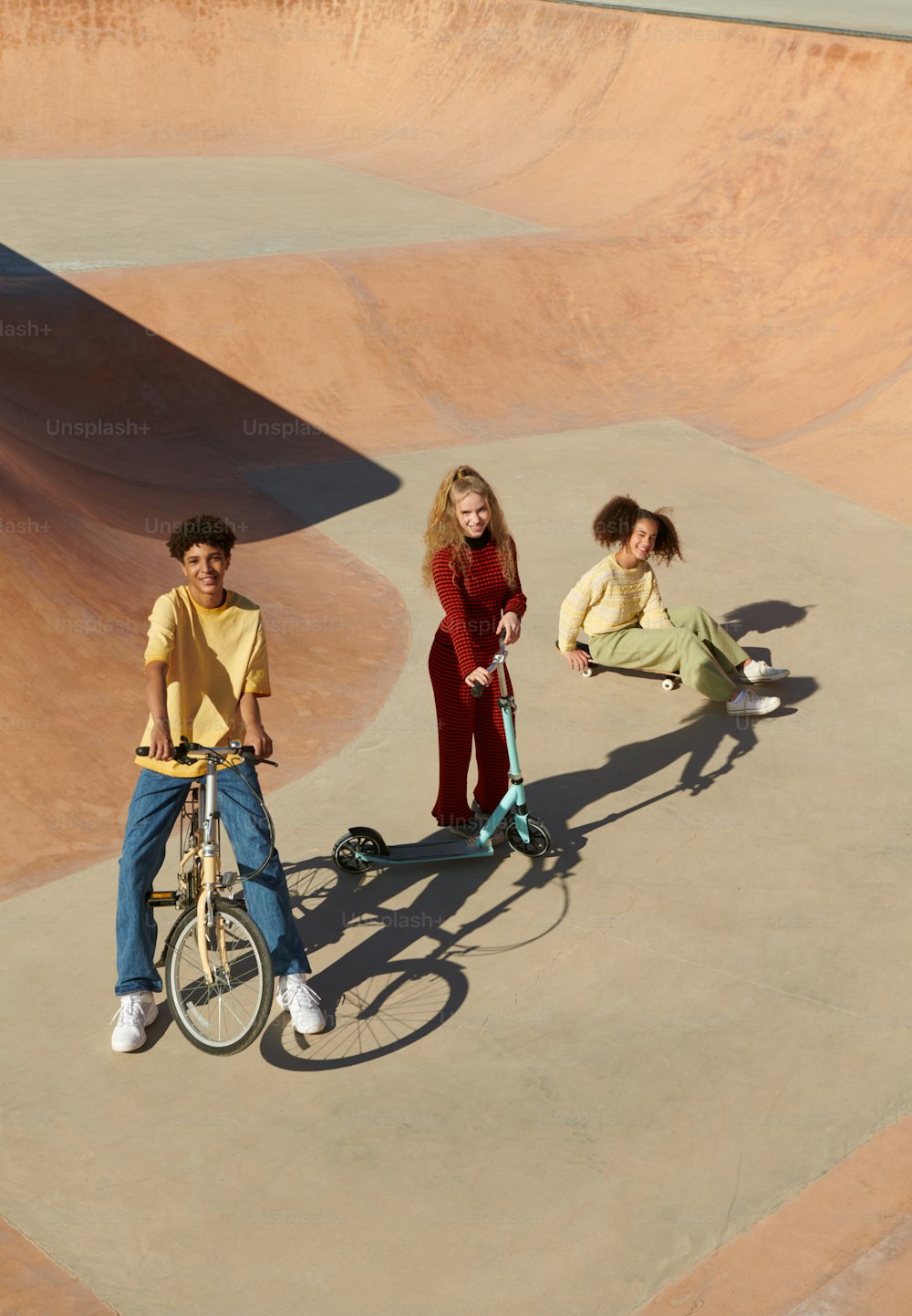 three young people riding bikes in a skate park