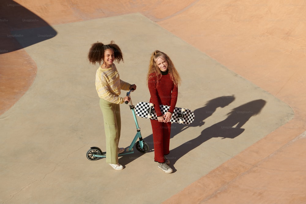 two girls standing next to each other on a skateboard
