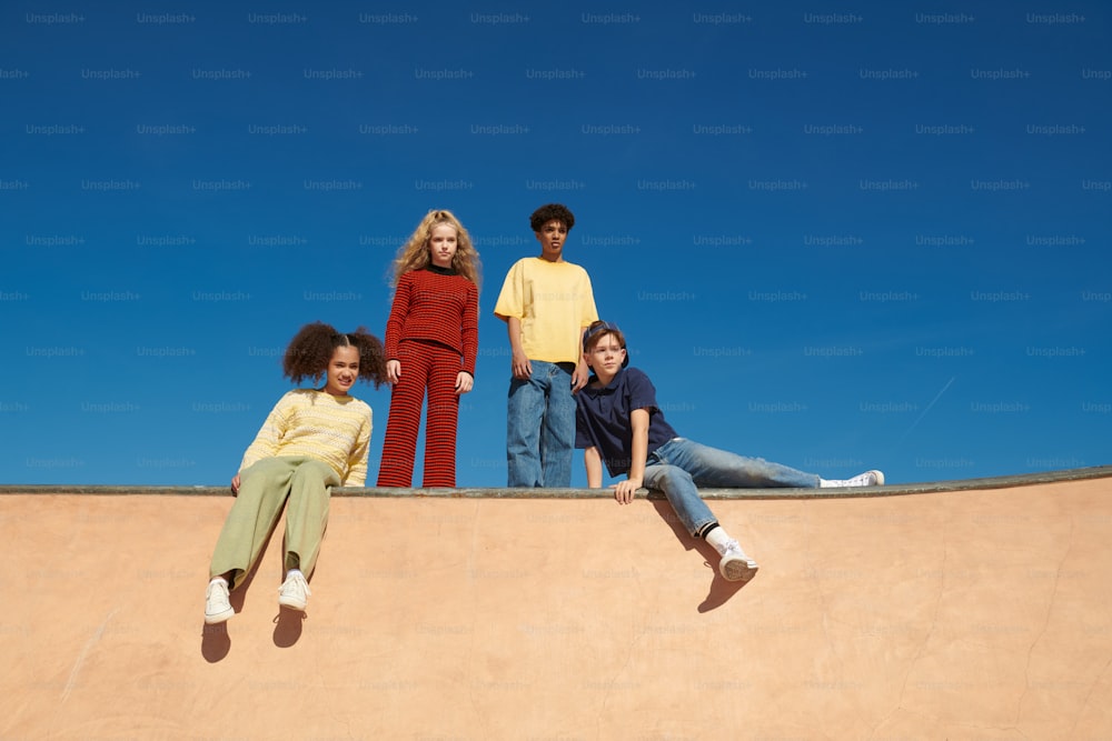 a group of young people sitting on top of a skateboard ramp