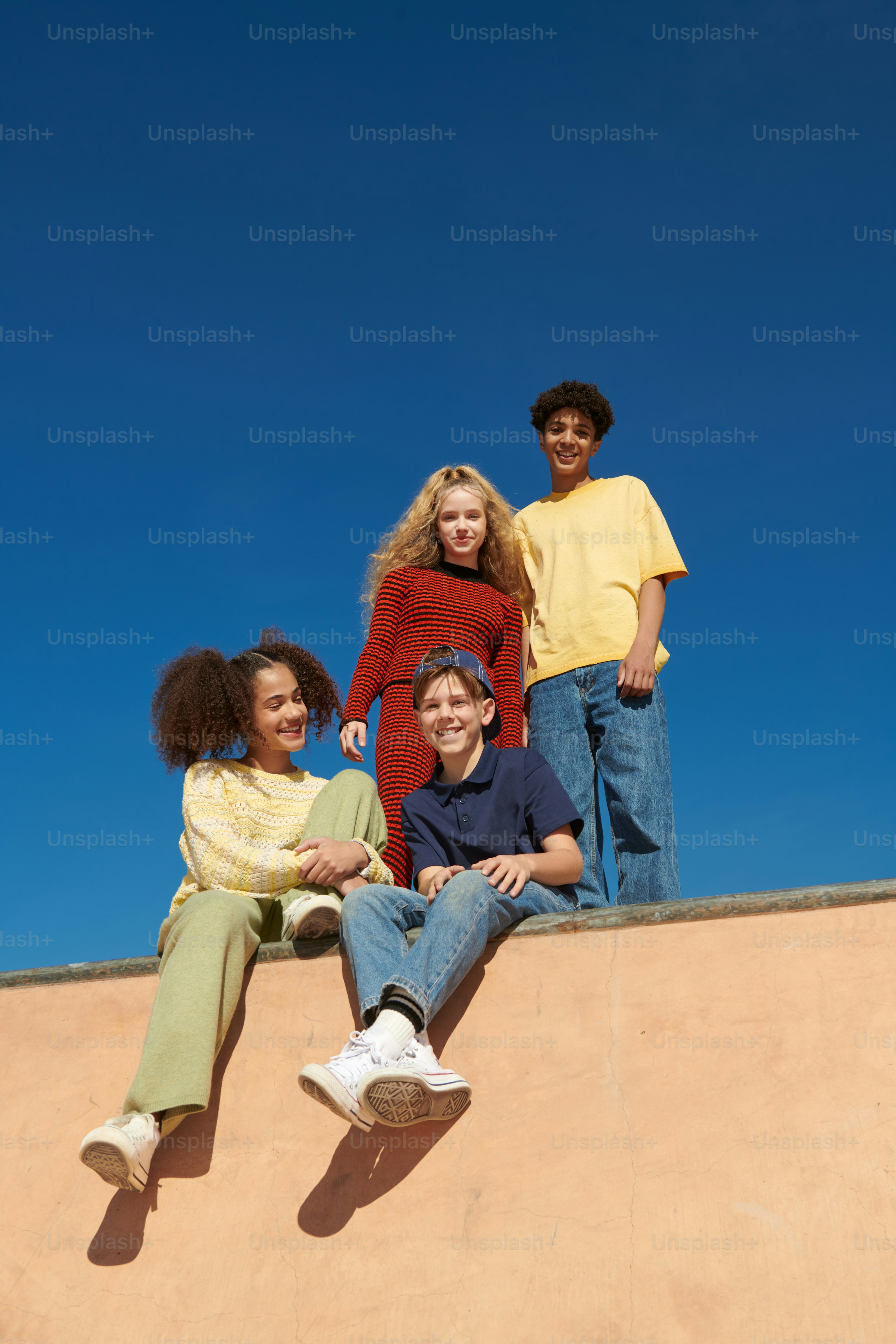Un grupo de jóvenes sentados en la parte superior de una rampa de patineta