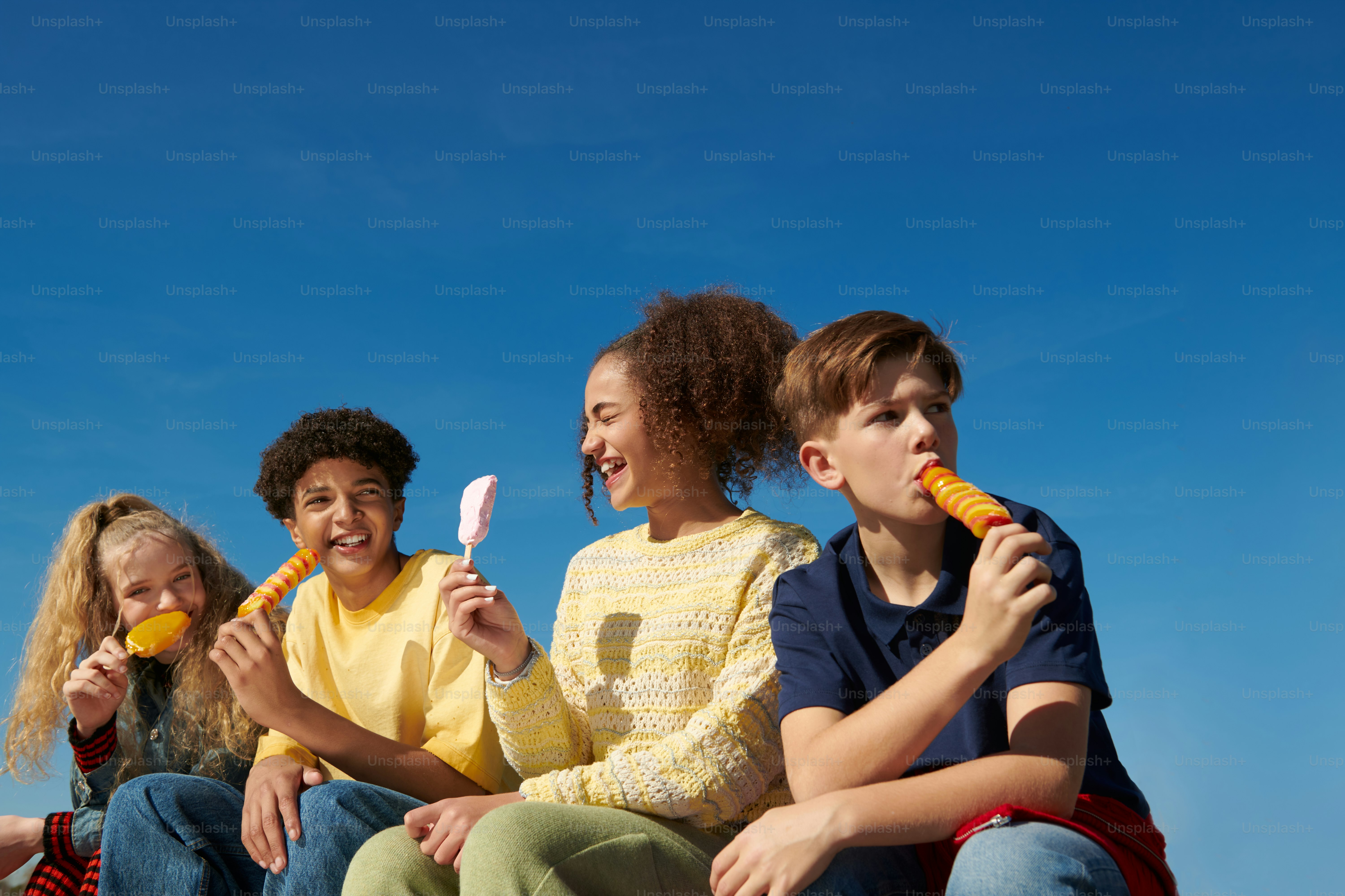 a group of kids sitting on a bench brushing their teeth