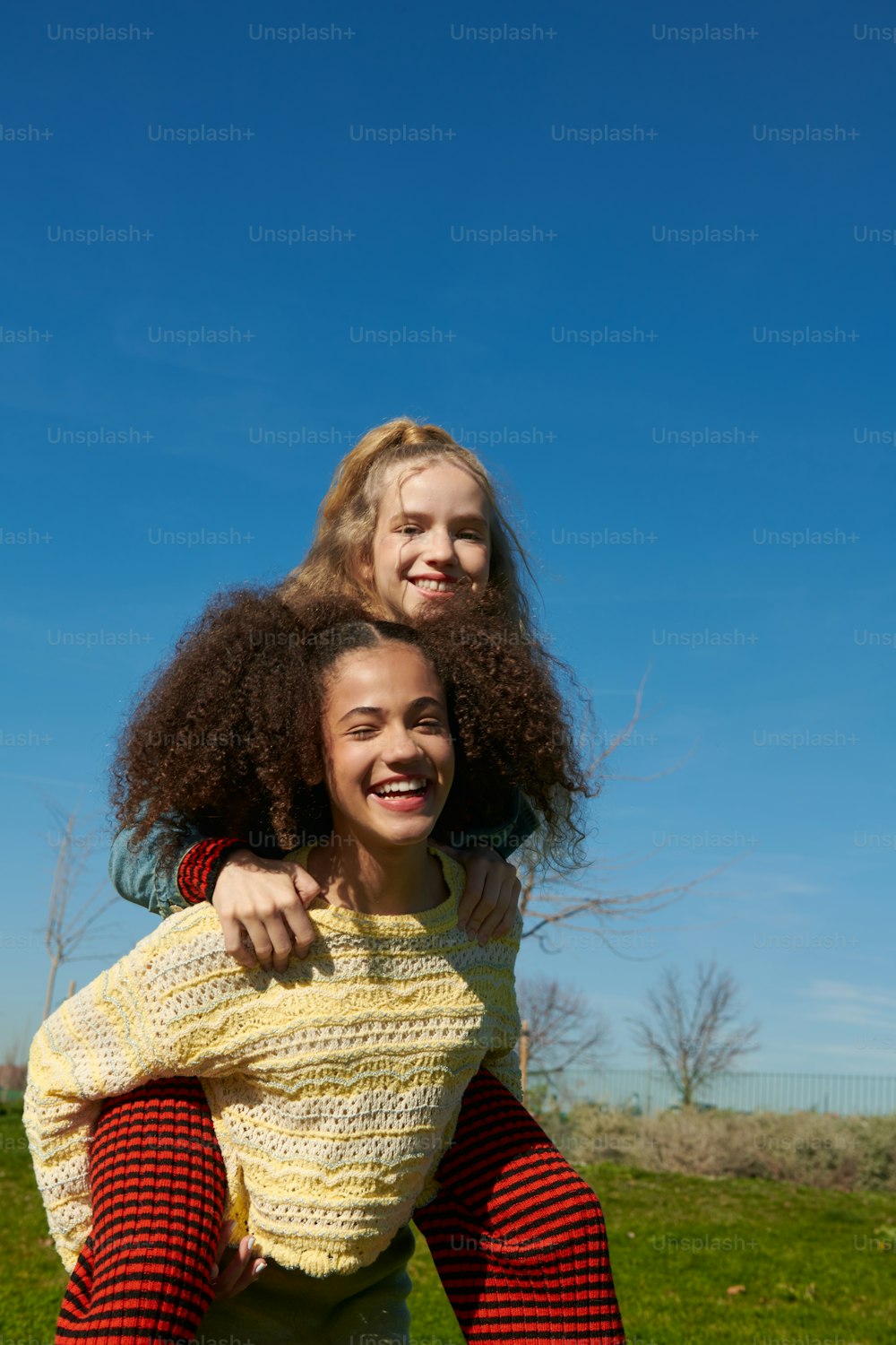 two young girls hugging each other in a field