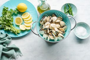 a blue colander filled with clams and lemons