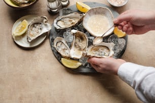 a plate of oysters on a table with lemon wedges