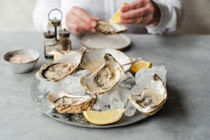 a plate of oysters on ice with lemon wedges