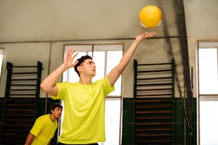 a man in a yellow shirt is playing with a yellow ball