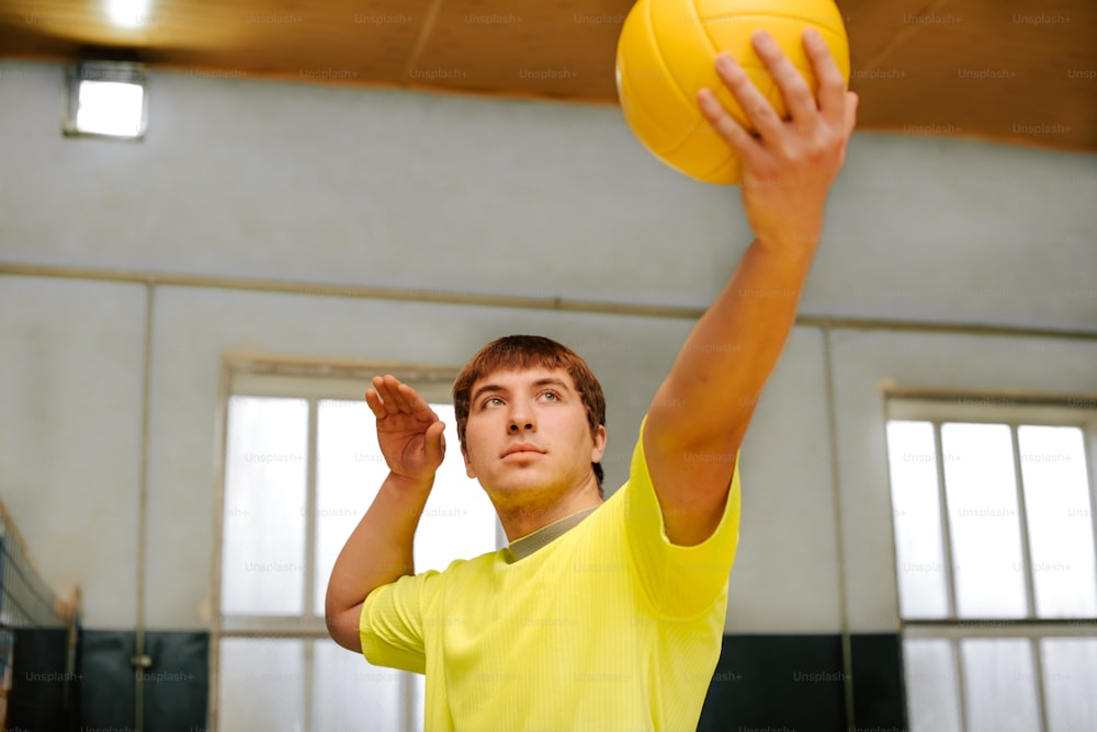 a man in a yellow shirt holding a yellow ball