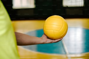 a person holding a yellow volleyball in their hand