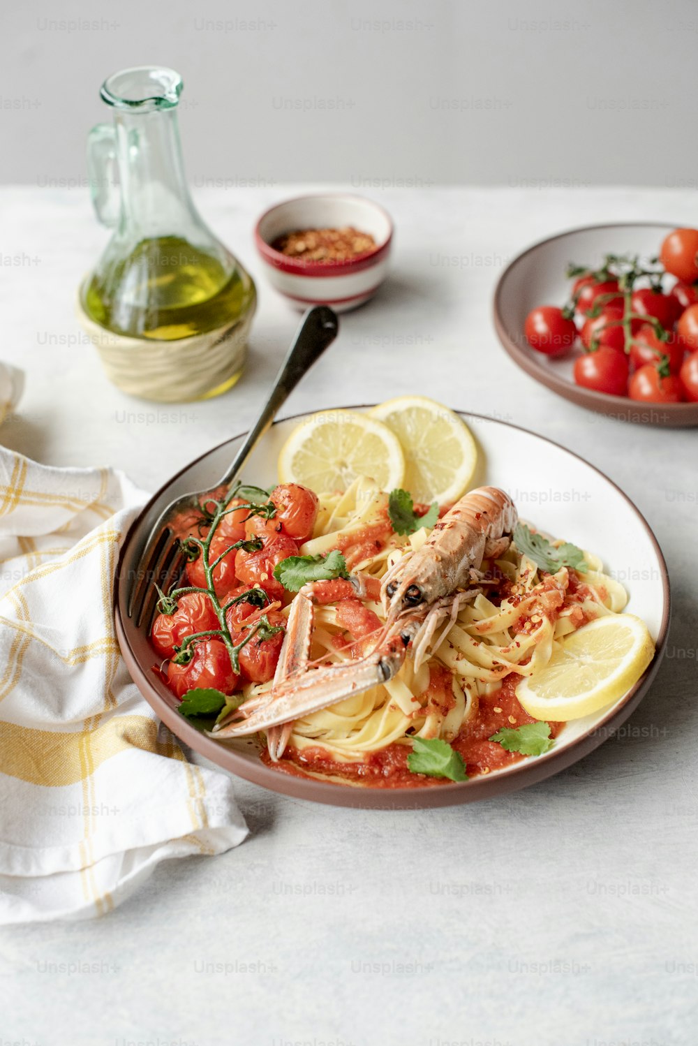 a plate of pasta with shrimp, tomatoes, and herbs