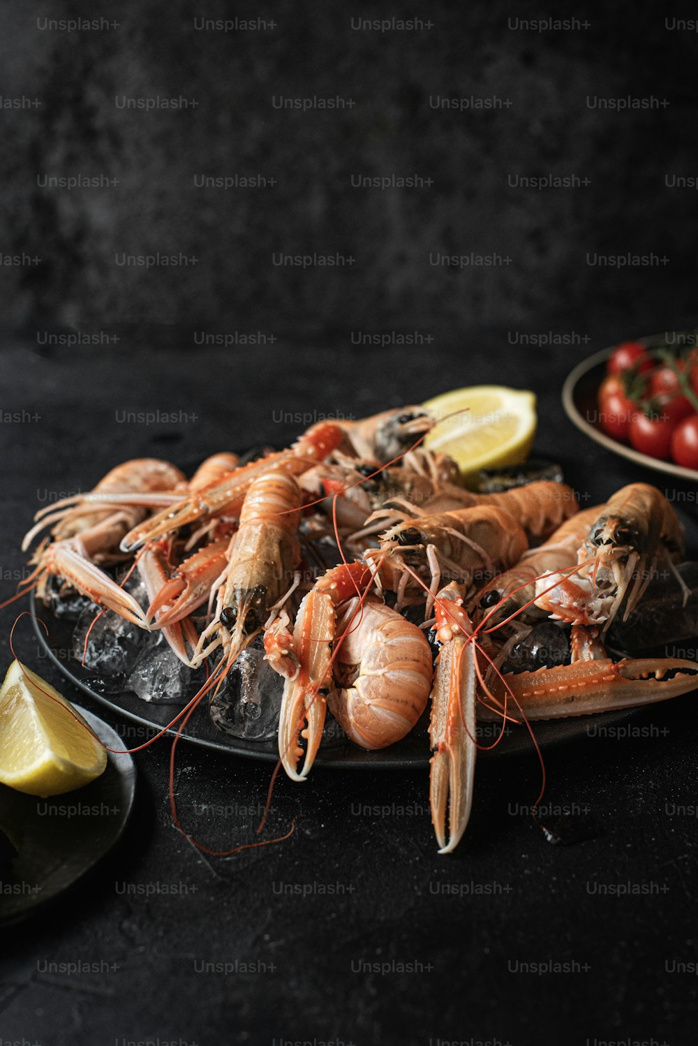 a platter of fresh lobsters with lemon wedges and tomatoes