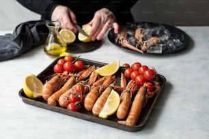 a tray of lobsters, lemons and tomatoes on a table