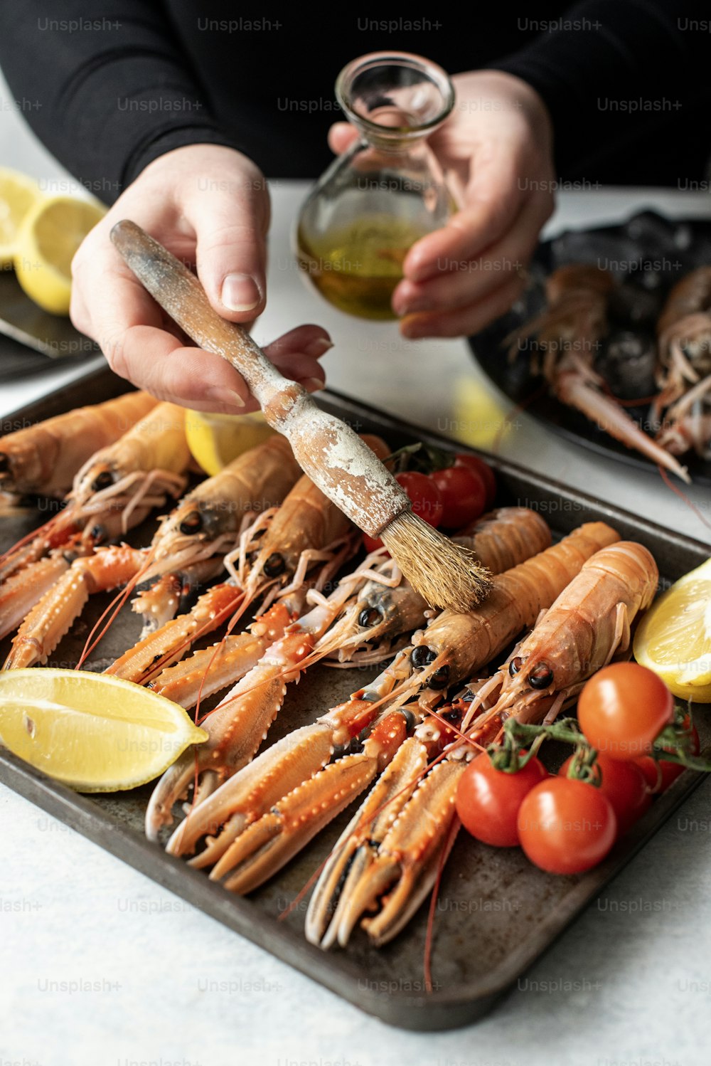 a person is holding a spoon over a tray of lobsters