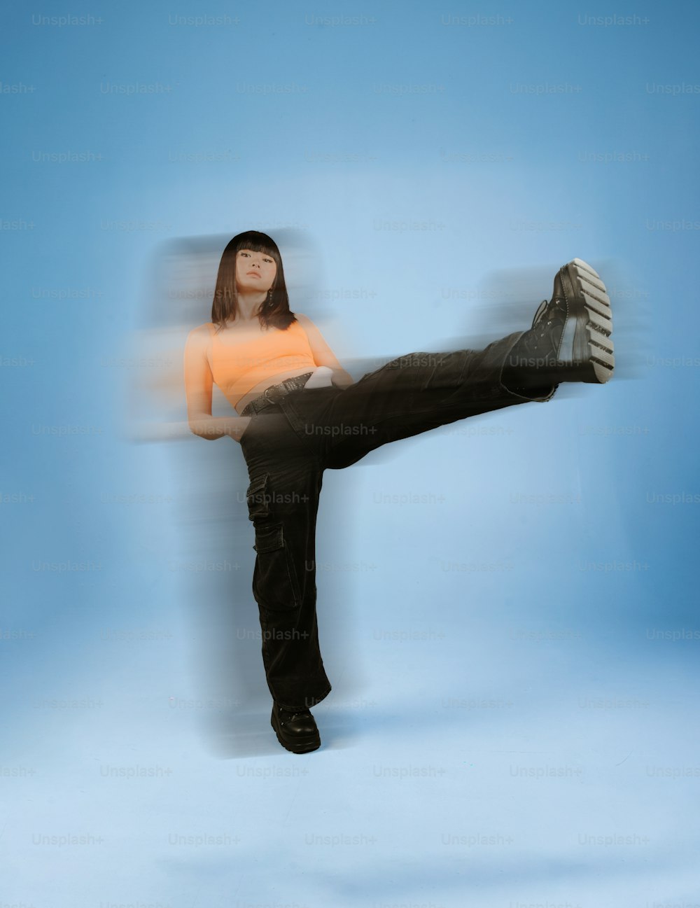 a woman in orange shirt doing a kick kick