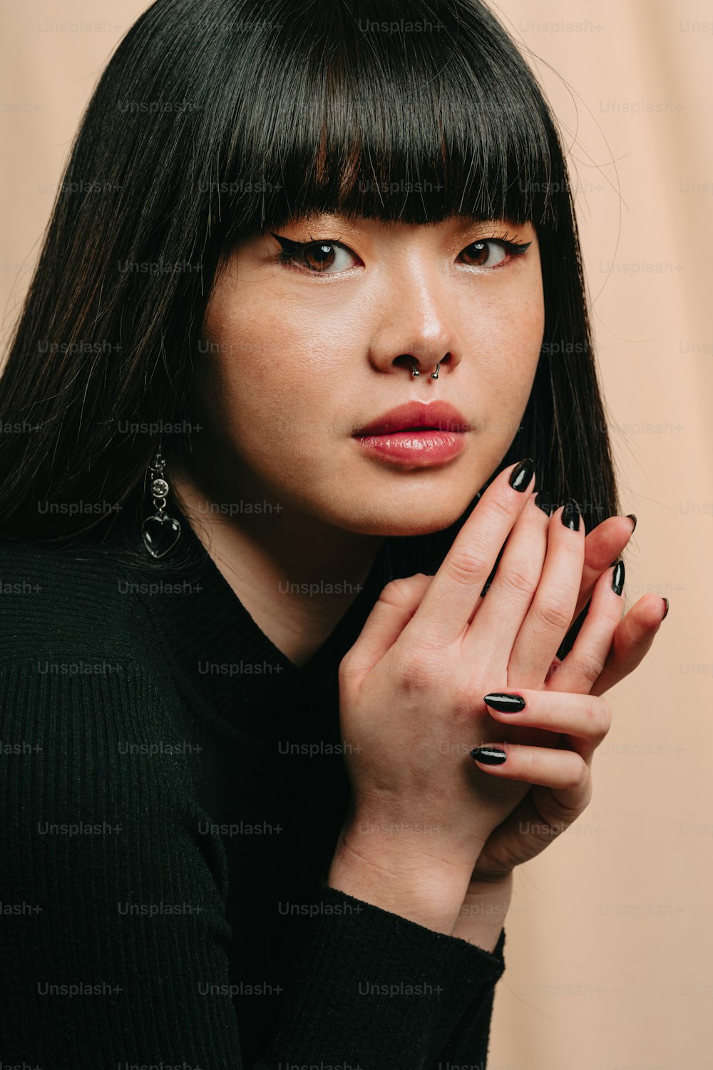 una mujer con esmalte de uñas negro sosteniendo su mano cerca de su cara