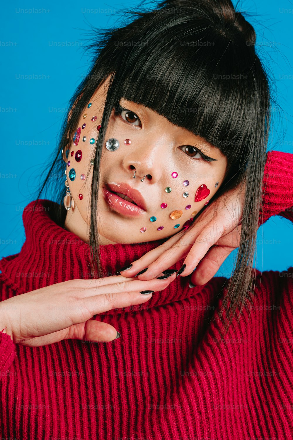 a woman with a red sweater and colorful decorations on her face