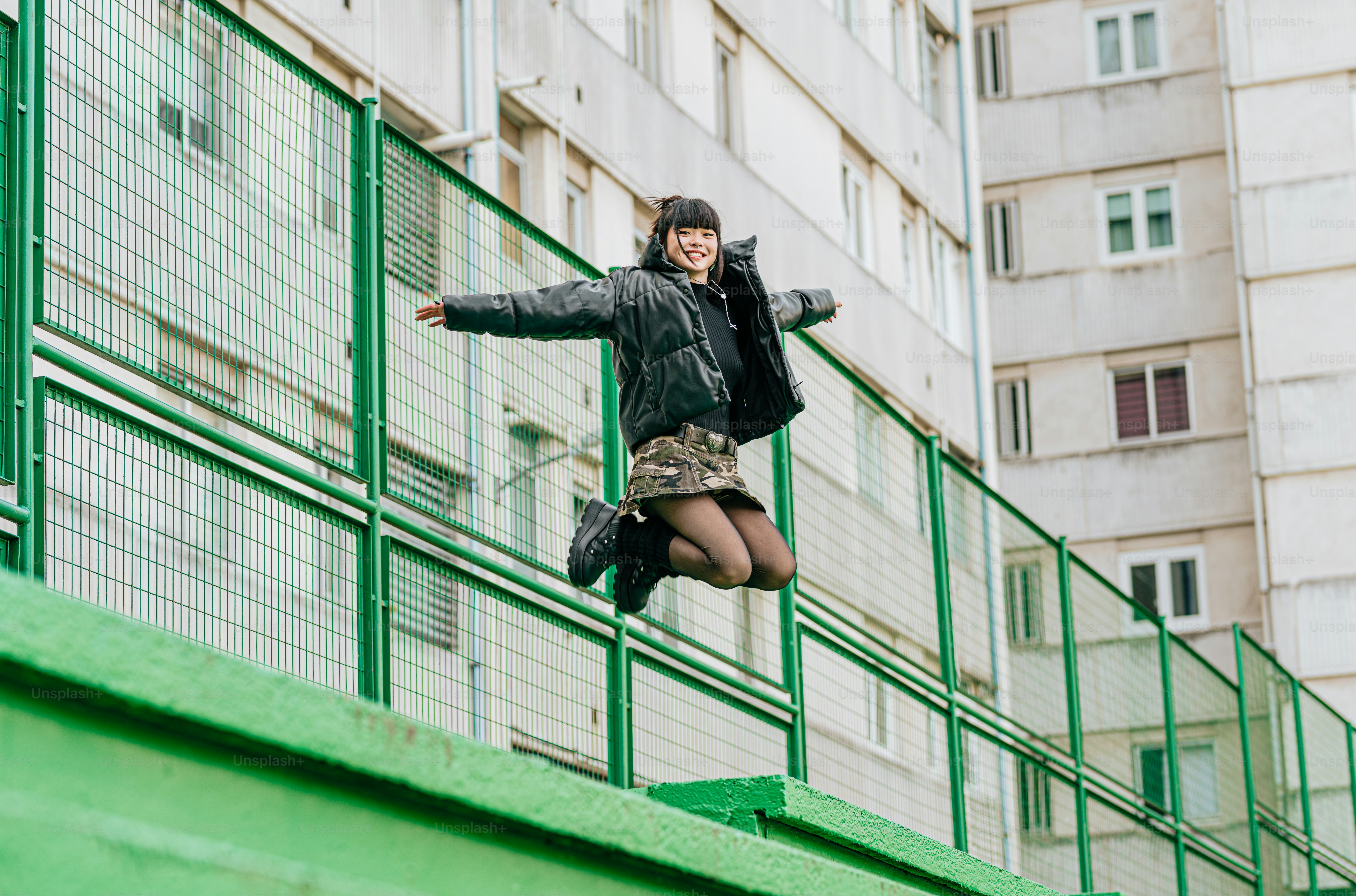 黒いジャケットを着た女性がスケートボードでトリックをしている