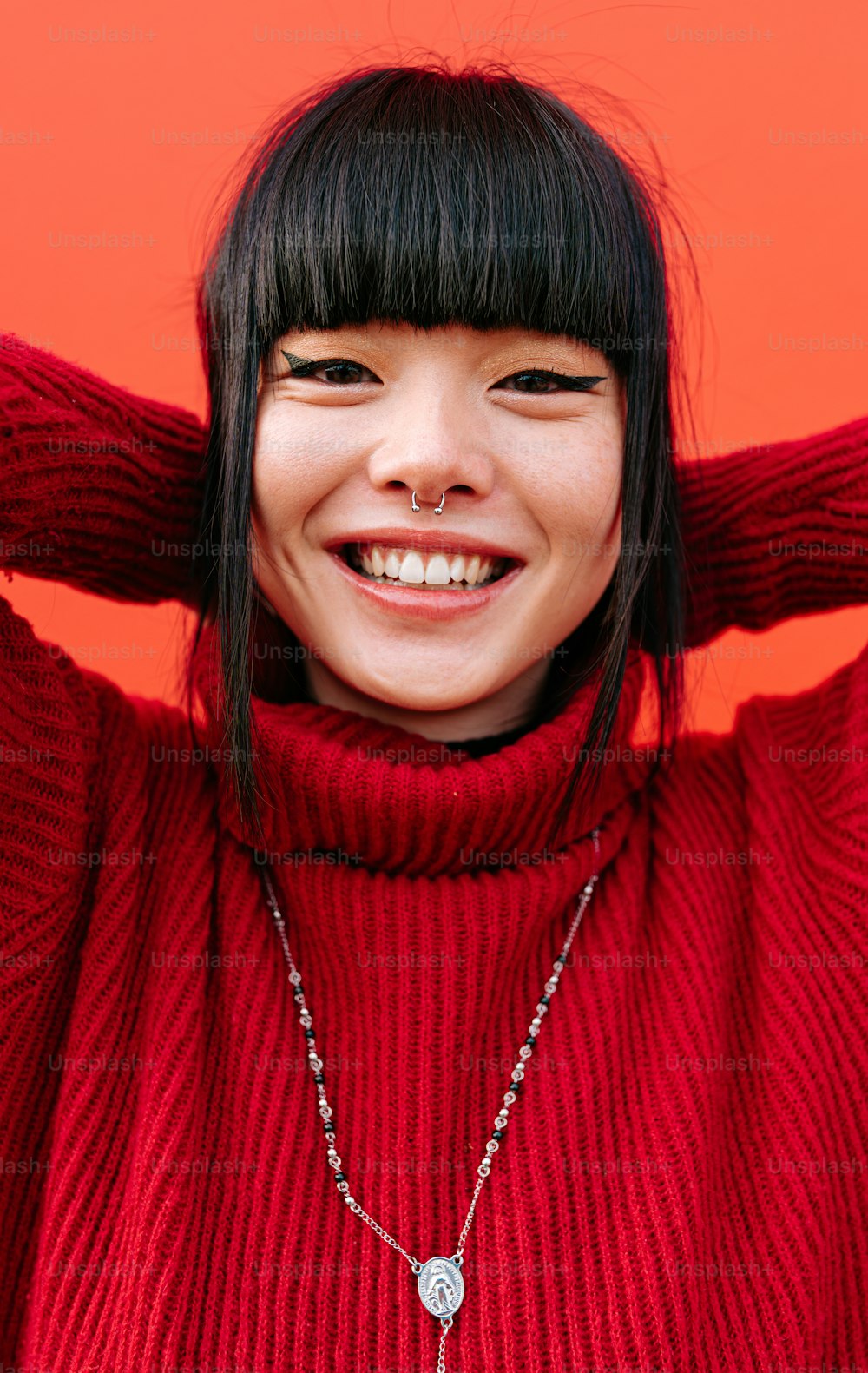 a woman wearing a red sweater and a silver necklace