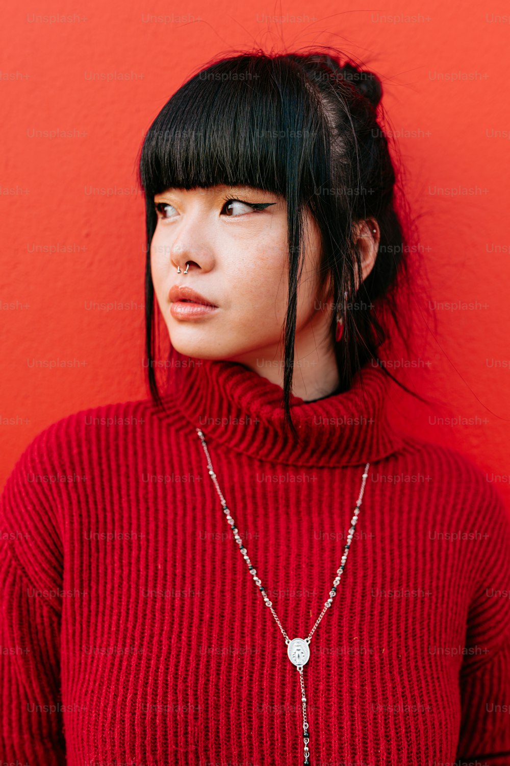 a woman with black hair wearing a red sweater