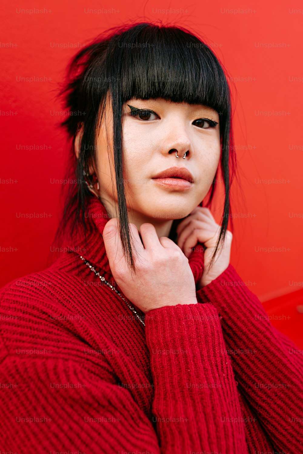 a woman with black hair wearing a red sweater