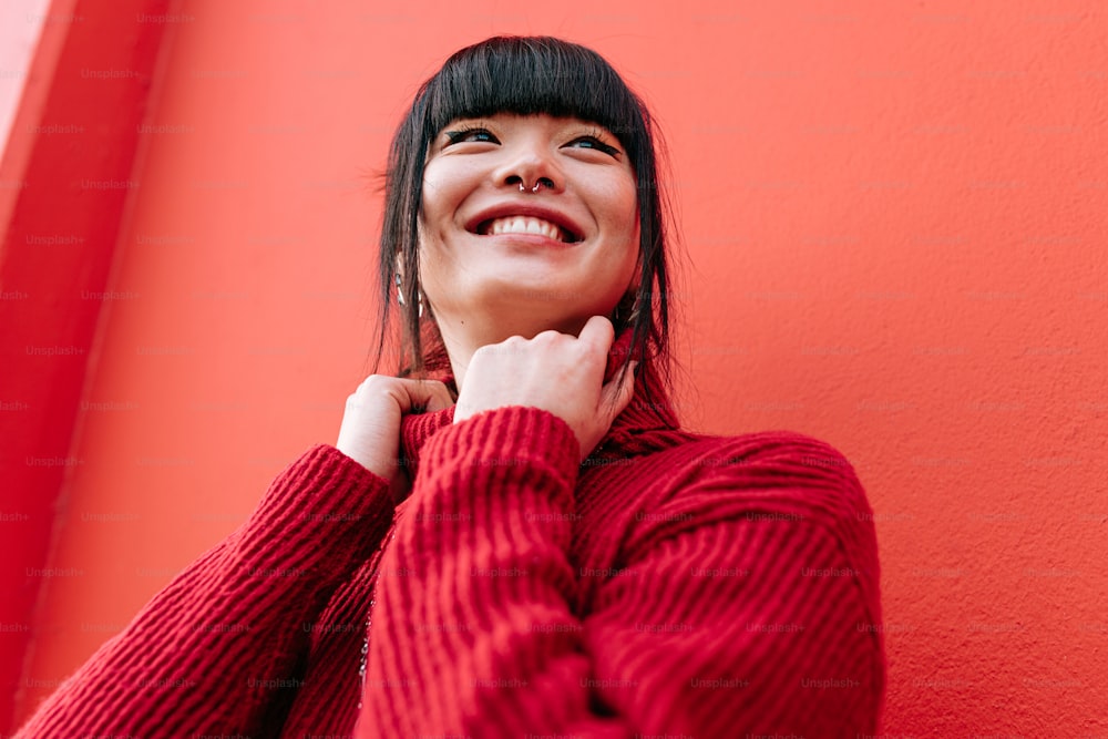 a woman smiles while leaning against a red wall