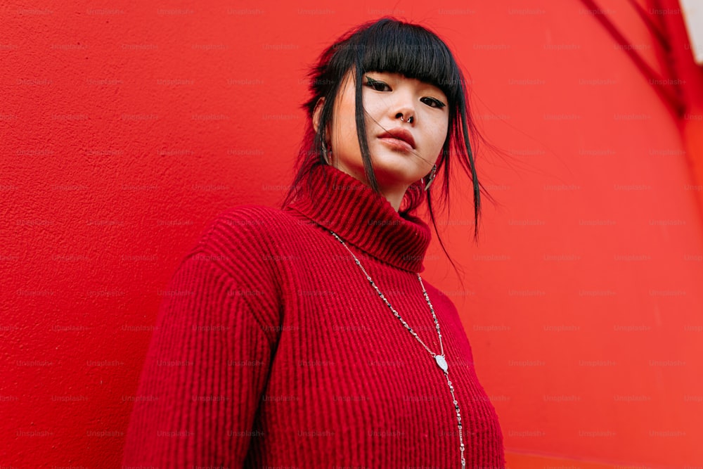 a woman in a red sweater standing against a red wall