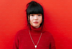 a woman in a red sweater standing against a red wall