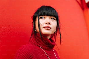 a woman in a red turtle neck sweater standing in front of a red wall