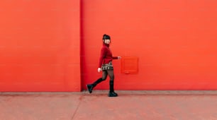a woman walking past a red wall