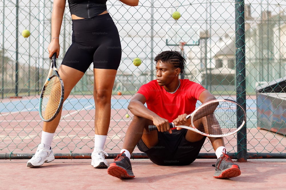 a man kneeling down next to a woman holding a tennis racquet
