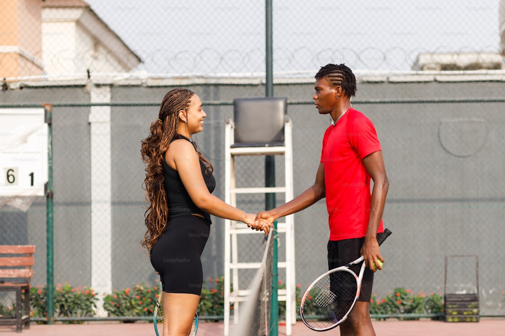 un uomo e una donna che si stringono la mano su un campo da tennis