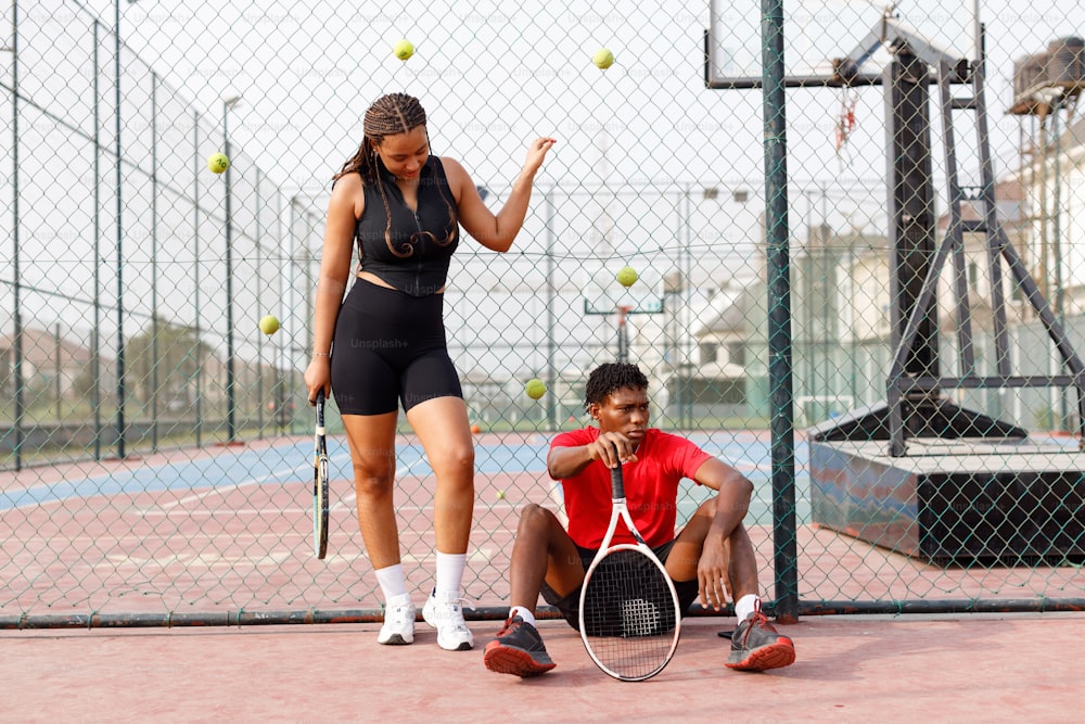 a man kneeling down next to a woman holding a tennis racquet